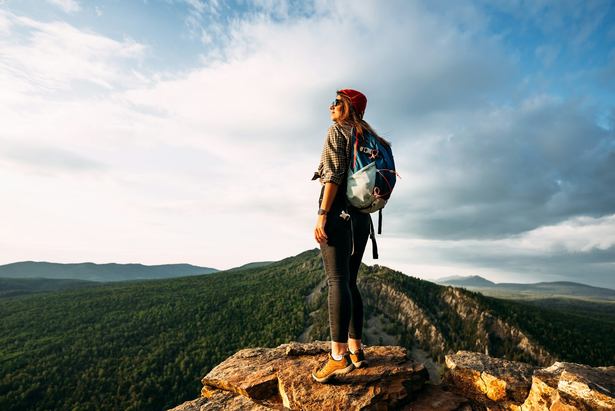 A woman meets the sunset in the mountains. Man travels in the mountains. Mountain tourism