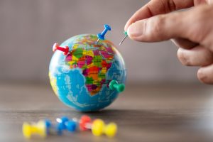 Closeup image of hand putting pins on world globe.