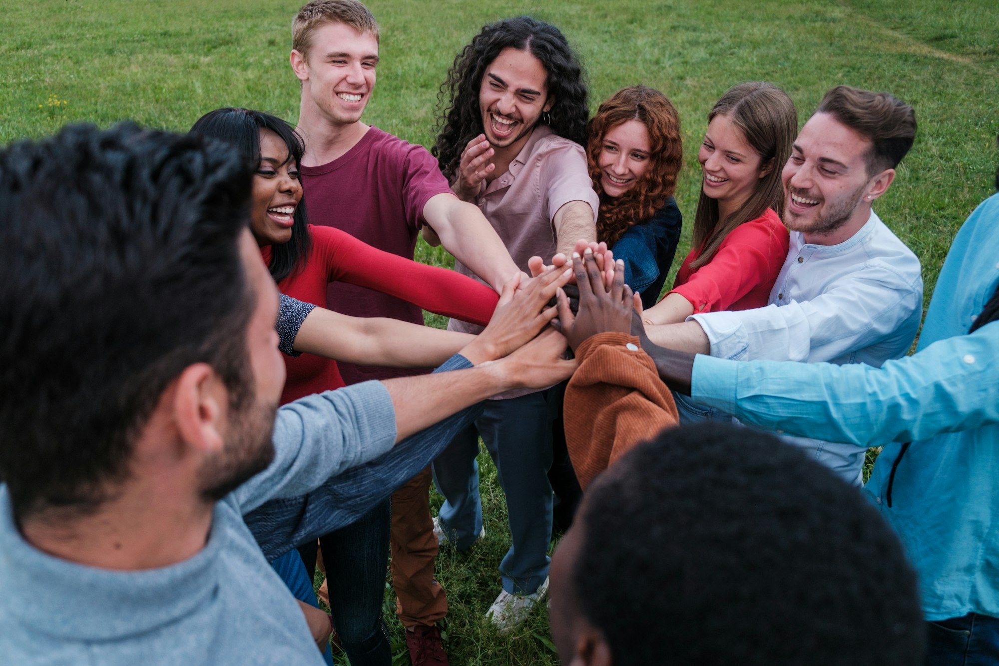 Group of culturally diverse friends joining hands representing teamwork